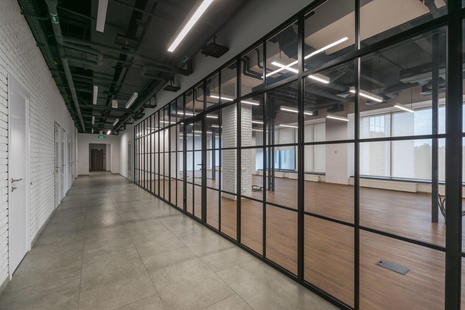 An open space of a modern office with panoramic windows and glass partitions. The room is decorated in loft style. An open space of a modern office with panoramic windows and glass partitions. The room is decorated in loft style.